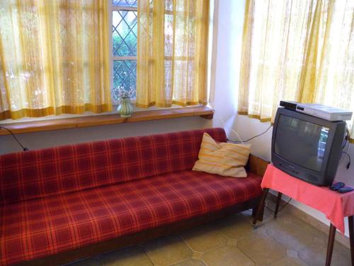 a living room with a red couch and a tv at Holiday home in Balatonfenyves 18357 in Balatonfenyves