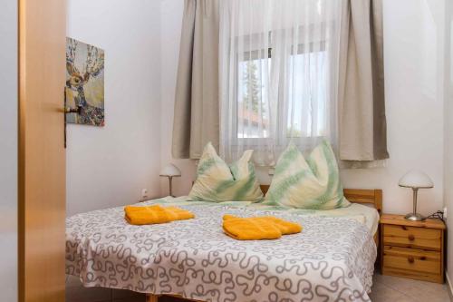 バラトンケレストゥールにあるHoliday home in Balatonmariafürdo 19492のベッドルーム1室(オレンジ色の枕と窓付)
