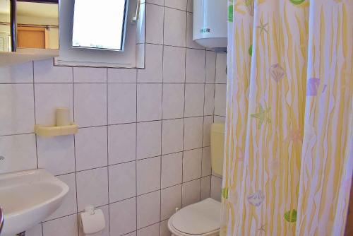 ein Bad mit einem Duschvorhang und einem WC in der Unterkunft Apartment Lopar, Primorje-Gorski Kotar 6 in Lopar