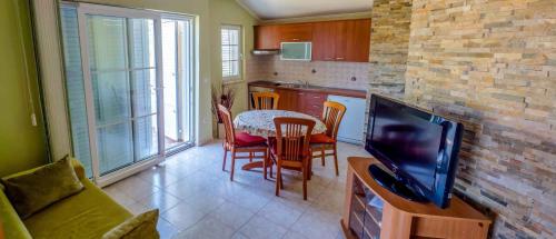 uma cozinha com uma mesa e uma televisão num quarto em Apartment Banjol 23 em Rab