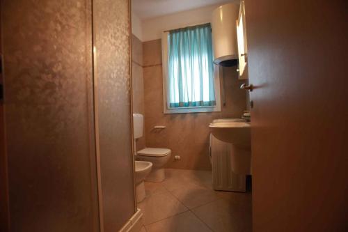 baño con aseo y lavabo y ventana en Apartment in Rosolina Mare 15, en Rosolina Mare