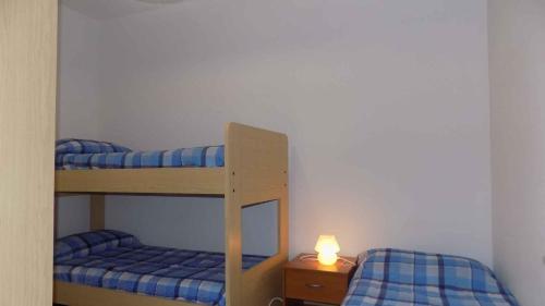 Apartment in Eraclea Mare 25654 في ايراكليا ماري: سريرين بطابقين في غرفة بها شمعة