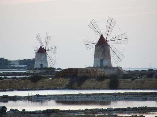 two windmills sitting on top of a body of water at Lilybeo Village in Marsala
