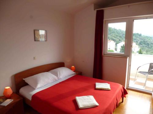 a bedroom with a bed with a red blanket and a window at Apartment Barbat 9 in Barbat na Rabu