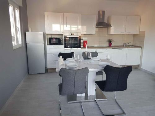 cocina con mesa, sillas y nevera en Apartment Lopar 12, en Lopar