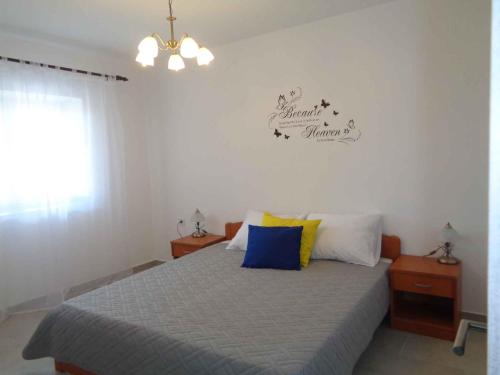 1 dormitorio con 1 cama con almohadas azules y amarillas en Two-Bedroom Apartment Lopar near Sea 2 en Lopar