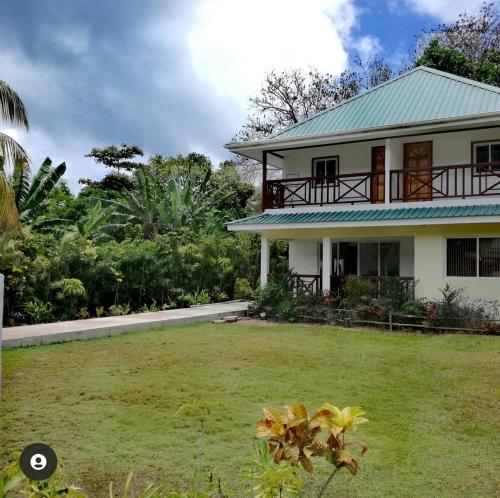 a white house with a green roof and a yard at Lucy's guesthouse in La Digue