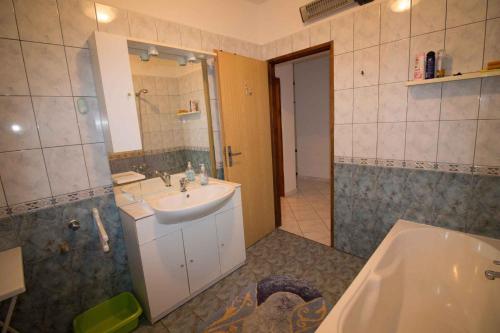 a bathroom with a sink and a mirror and a tub at Apartment Kampor 1 in Kampor