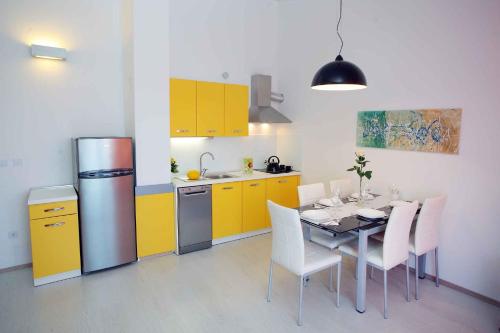 a kitchen with yellow cabinets and a table with white chairs at Apartment Banjole 1 in Banjole