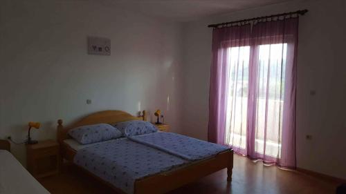 a bedroom with a bed and a window with pink curtains at Apartment Lopar, Primorje-Gorski Kotar 4 in Lopar