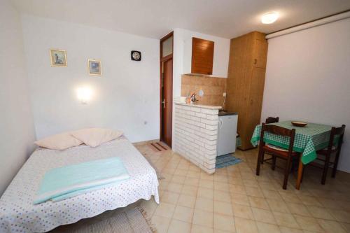 a bedroom with a bed and a table and a kitchen at Studio Apartment Pula near Sea 2 in Vintijan