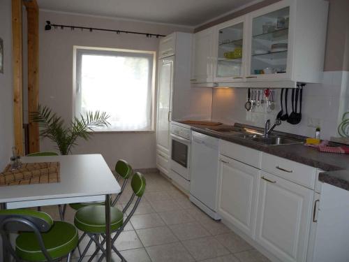 a kitchen with white cabinets and a table and green chairs at Holiday home in Rambin/Insel Rügen 3062 in Rambin