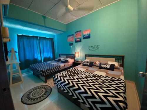 two beds in a room with blue walls at Suhana HomeStay Semporna - Cozy Home in Semporna