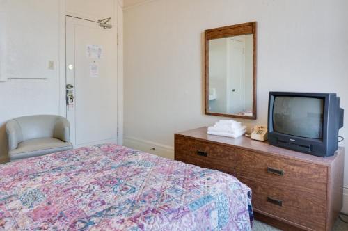 a bedroom with a bed and a tv and a mirror at Aida Plaza Hotel in San Francisco