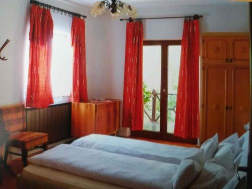 EbhegyにあるApartment Balatonszarszo/Balaton 20085の赤いカーテンとベッド、窓が備わるベッドルーム1室が備わります。