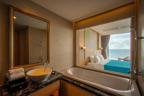 uma casa de banho com uma banheira, um lavatório e um espelho. em Navada Beach Hotel em Nha Trang