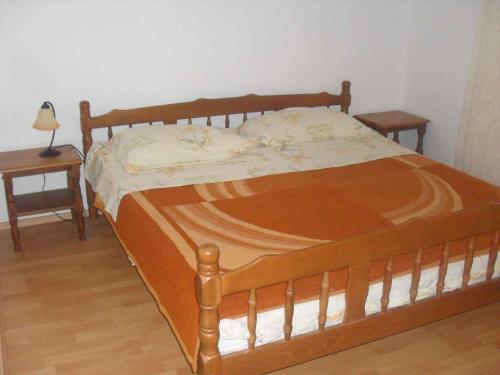 a wooden bed in a bedroom with two tables at Apartment Lopar 14 in Lopar