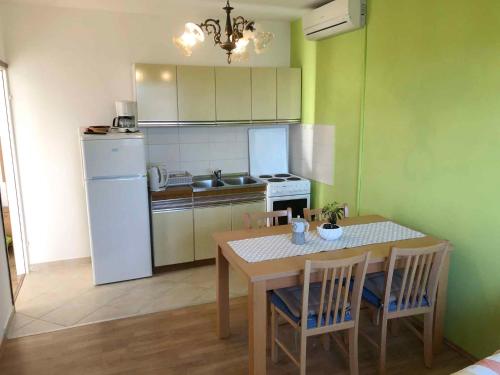 a kitchen with a table and a white refrigerator at Apartment Kampor 3 in Kampor