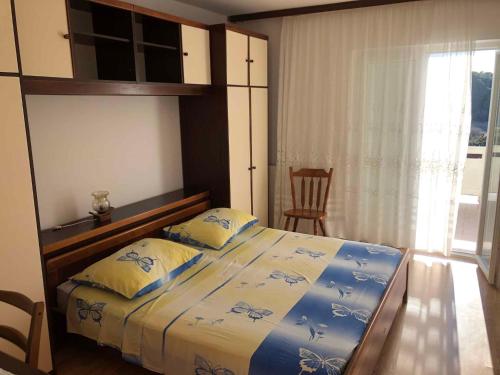 a bedroom with a bed with two pillows and a window at Apartment Kampor 3 in Kampor