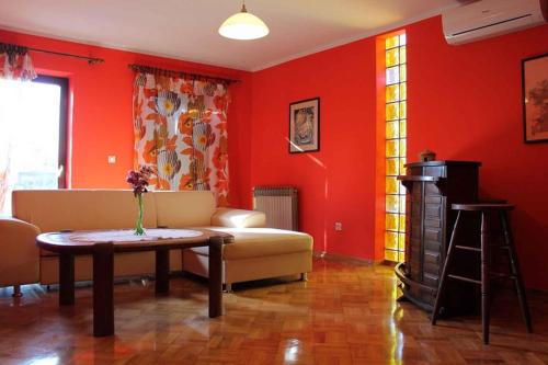 a living room with red walls and a couch and a table at Apartment Valbandon 8 in Štinjan