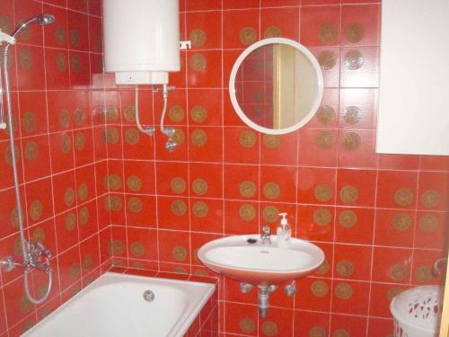 a red tiled bathroom with a sink and a mirror at Apartment Medulin 12 in Medulin