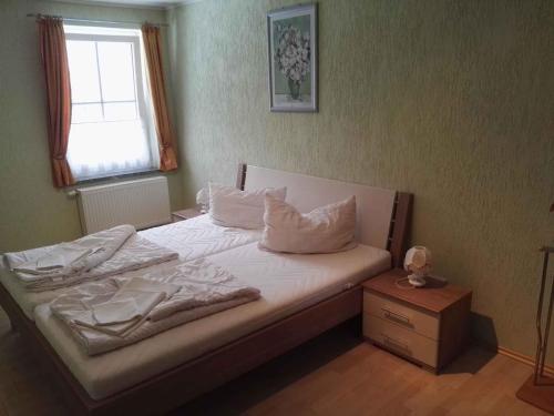 1 cama con sábanas y almohadas blancas y ventana en Apartment Sayda 3, en Pilsdorf