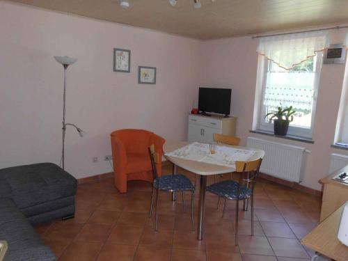 ein Wohnzimmer mit einem Tisch, Stühlen und einem TV in der Unterkunft Apartment Sayda 1 in Pilsdorf