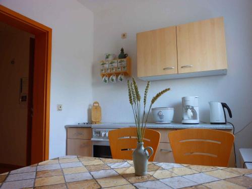 eine Küche mit einem Tisch und einer Vase mit einer Pflanze darin in der Unterkunft Apartment in Küstriner Vorland 2607 in Manschnow