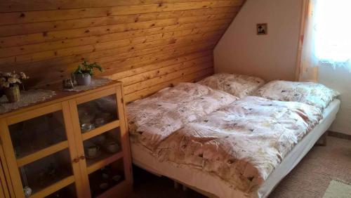 Holiday home in Pernink/Erzgebirge 1672 في Pernink: غرفة نوم بسرير وجدار خشبي