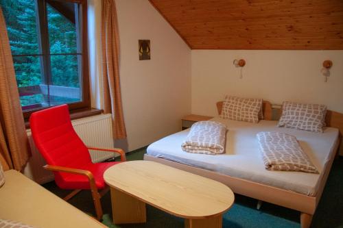 Cette chambre comprend deux lits et un fauteuil rouge. dans l'établissement Apartment Harrachov 6, à Nový Svět