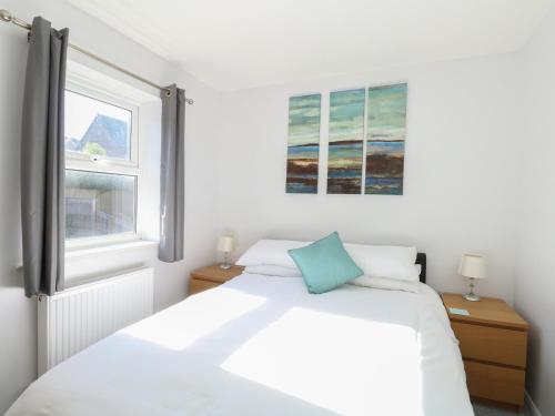 a white bedroom with a bed and two windows at Rockpools in Weymouth