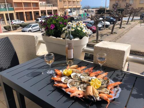 - une assiette de fruits de mer sur une table avec des verres à vin dans l'établissement Villa Magaly T4 à 50 m de la plage de Valras centre, à Valras-Plage