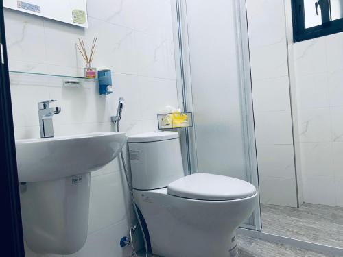 a white bathroom with a toilet and a sink at 舞艾湖民宿 in Hsing-wen
