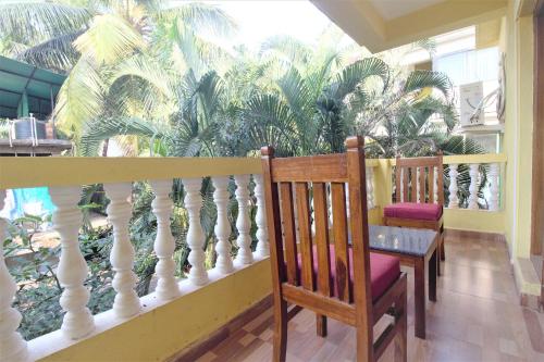 d'un balcon avec une table, des chaises et des palmiers. dans l'établissement Casa Joseph, à Candolim
