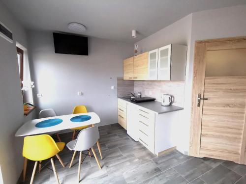 a kitchen with a table and some yellow chairs at Domki LUNA in Sarbinowo