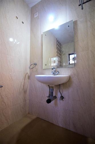 Un baño con un lavabo y un espejo en la pared. en Casa Joseph, en Candolim