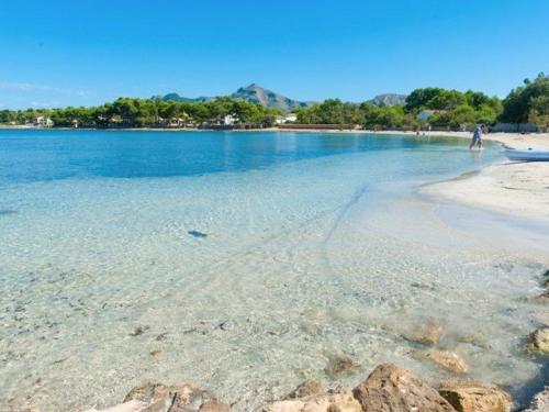 a beach with a person walking in the water at Ca S'Ingles in Alcudia