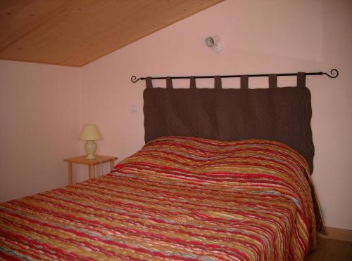1 dormitorio con 1 cama con una manta colorida en colombo, en Lacrouzette