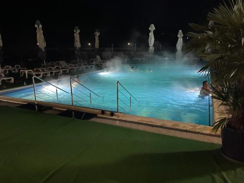 a large swimming pool with a fountain at night at Hotel Ostrov in Călimăneşti