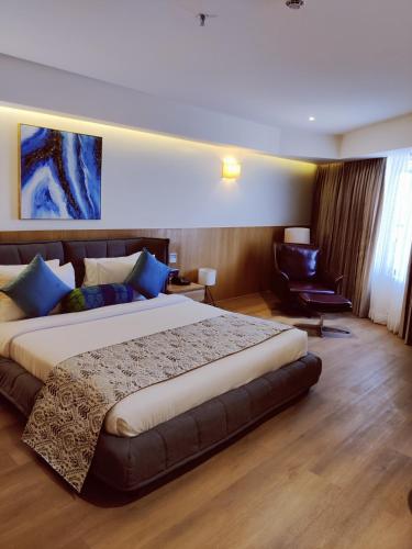 a bedroom with a large bed and a chair at The Fern Residency, Jamnagar in Jamnagar