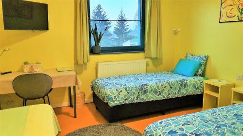 a room with two beds and a desk and a window at Hotel Amethist in Ramsel