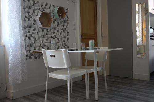 a dining room table with white chairs and a wall at CALODURUM in Chilleurs-aux-Bois