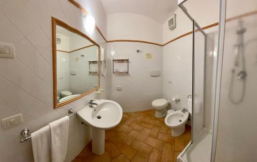 łazienka z umywalką, lustrem i toaletą w obiekcie Hotel Ristorante Le Querciolaie dei Ricci w mieście Fonteblanda