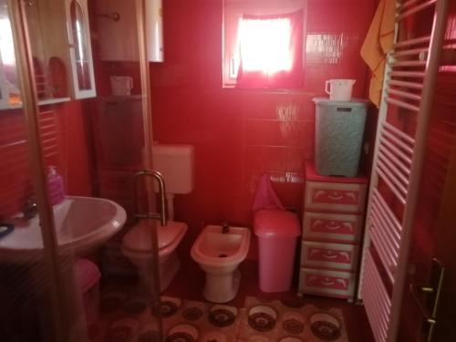een rode badkamer met een toilet en een wastafel bij Vila Anđelija in Velika Kladuša