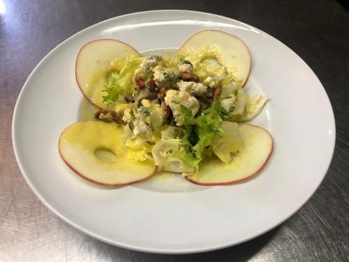 a white plate with apples and a salad on it at Hotel Seva in Seva