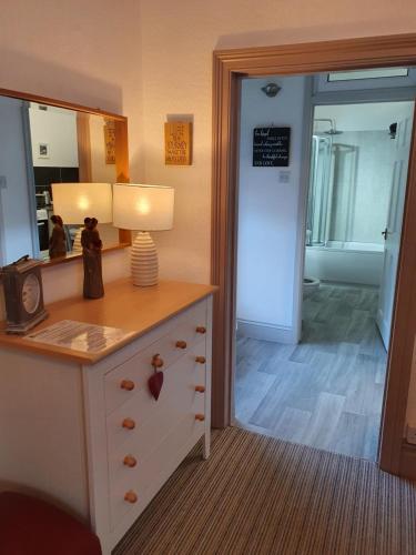 a room with a dresser with a mirror and a lamp at Caulfields Hotel in Burry Port