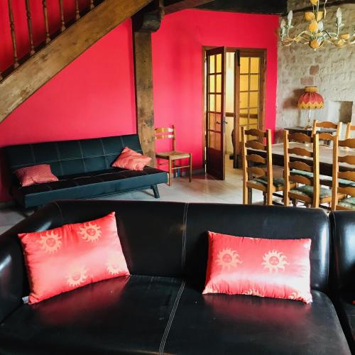 - un salon avec un canapé noir et des murs rouges dans l'établissement gite Le Verdier, à Nailhac