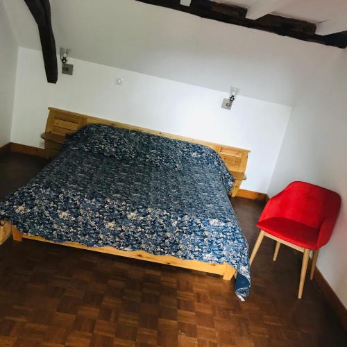 une chambre avec un lit et une chaise rouge dans l'établissement gite Le Verdier, à Nailhac