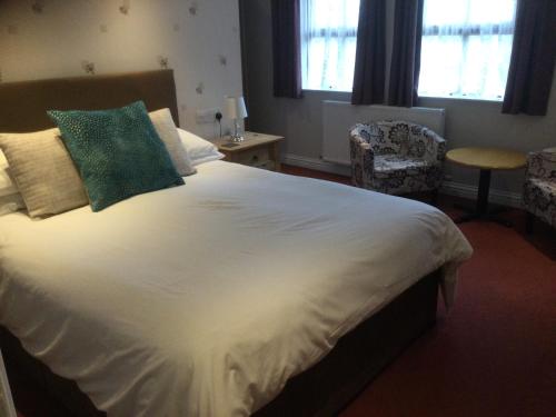 um quarto com uma grande cama branca e uma almofada verde em New Overlander Inn em Tenby