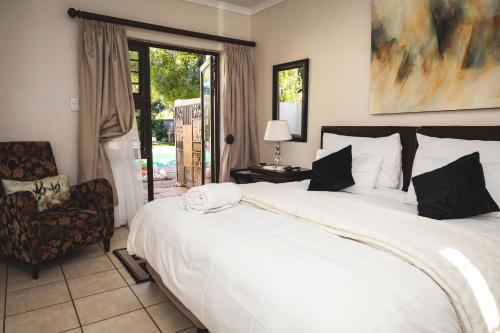 Un dormitorio con una gran cama blanca y una silla. en Be My Guest, en Upington